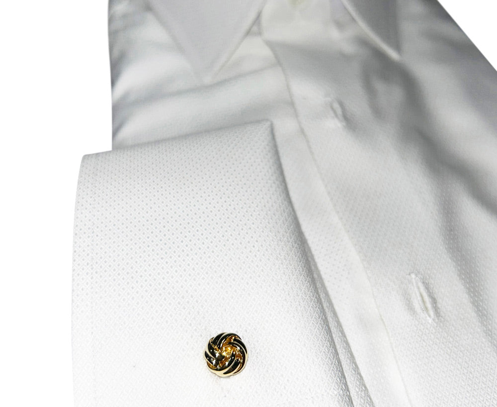 Close-up of a white shirt with a gold love-knot cufflinks on a white background
