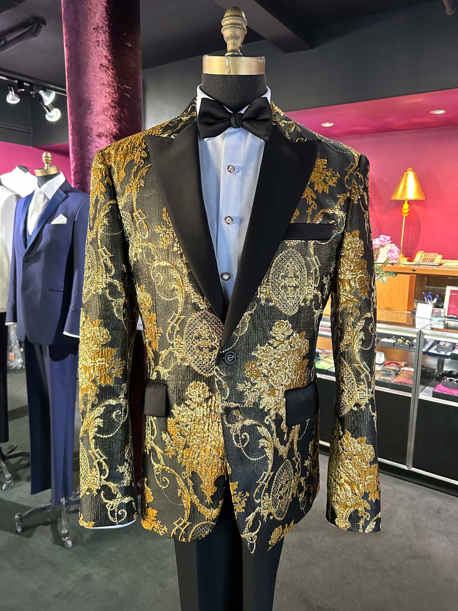 close up of a mannequin wearing a gold and black patterned tuxedo with black peak lapels inside a tuxedo shop