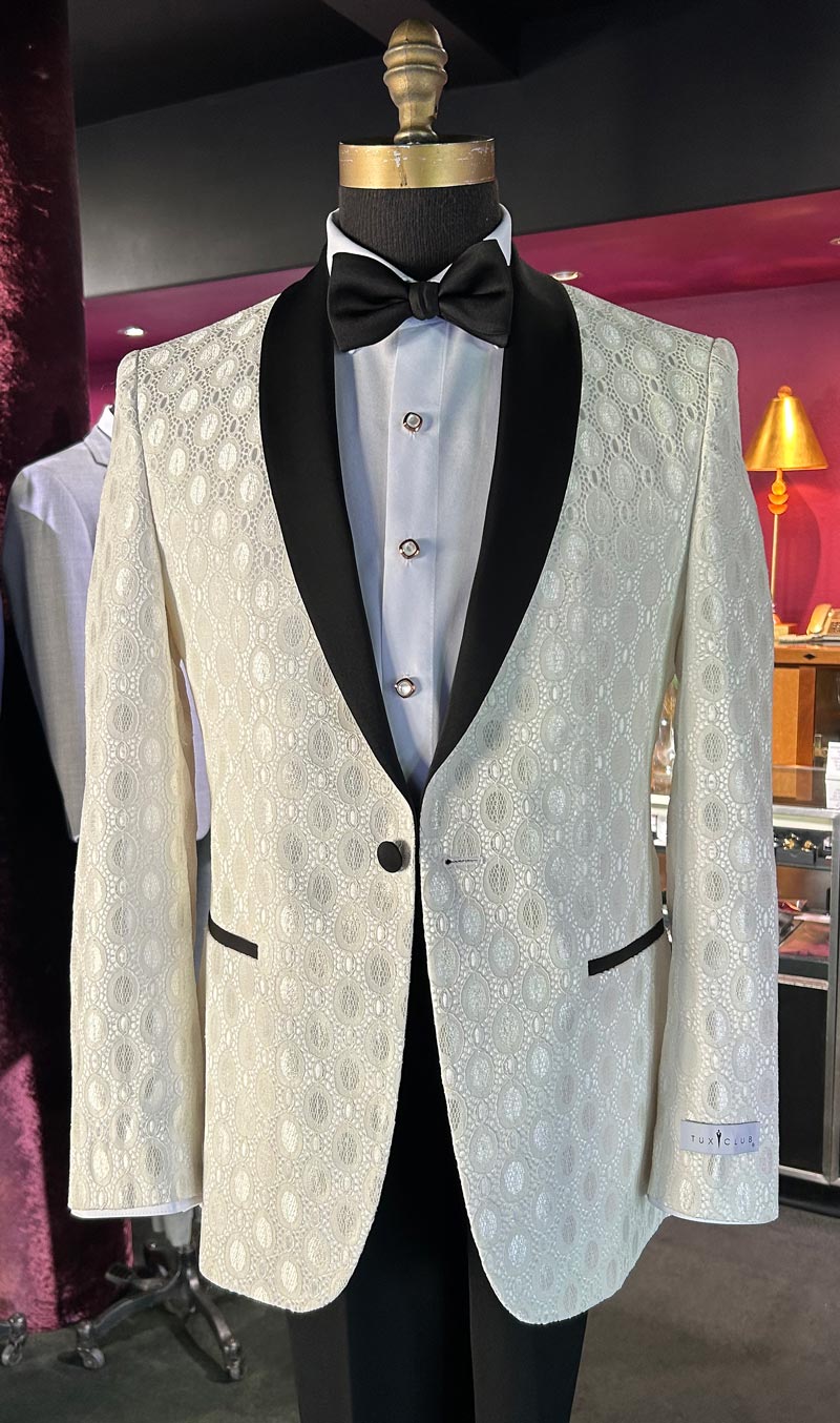 Close-up Ivory shawl collar tuxedo jacket with black lapels on a mannequin inside a tuxedo shop