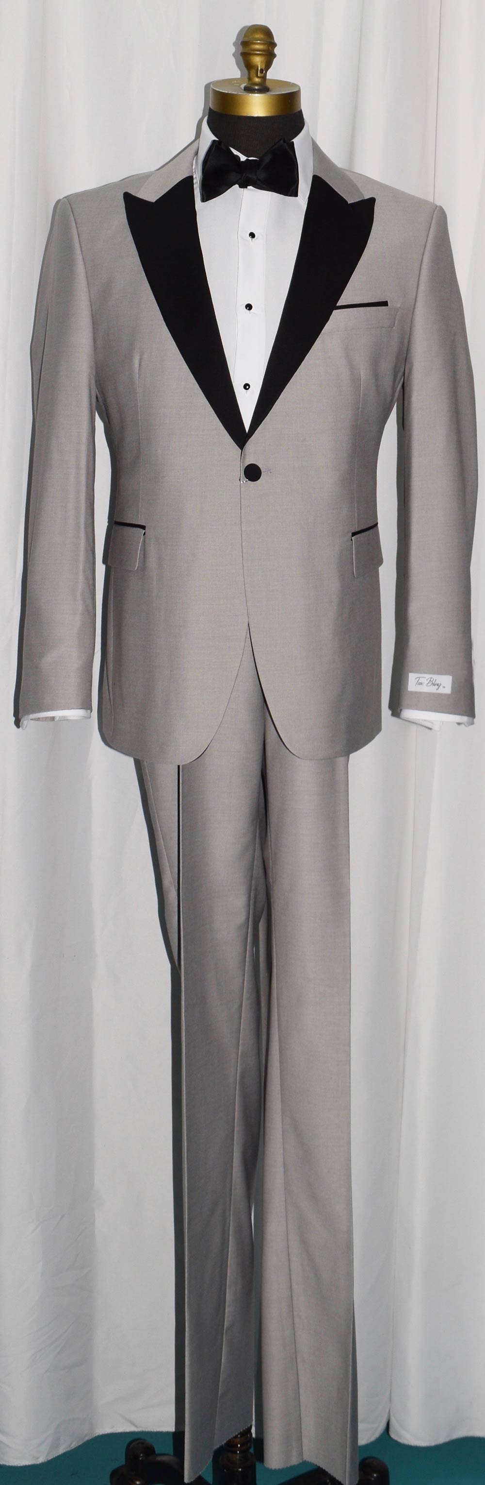 life size mannequin wearing light gray peak lapel tuxedo with black bow tie inside of a menswear shop