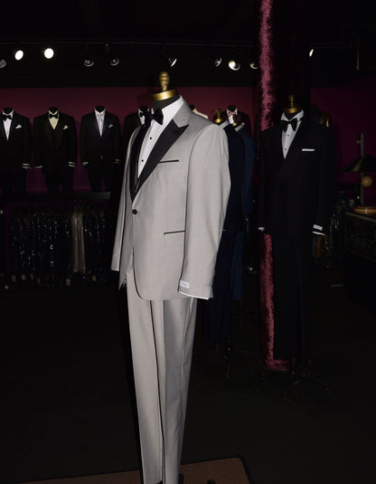 side view- life size mannequin wearing light gray peak lapel tuxedo with matching gray vest and black bow tie inside of a menswear shop