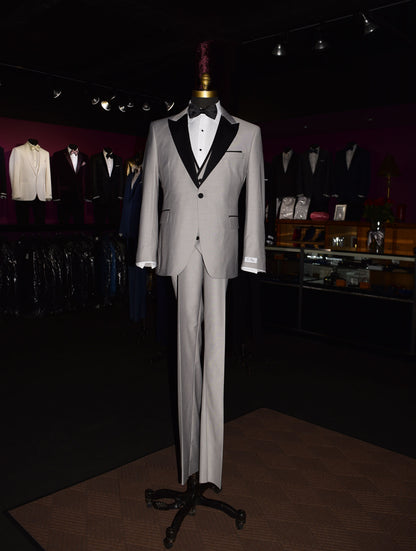 life size mannequin wearing light gray peak lapel tuxedo with matching gray vest and black bow tie inside of a menswear shop