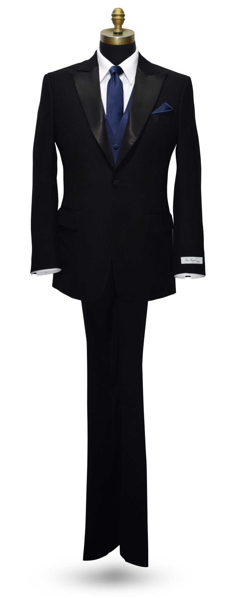 life size mannequin wearing a black peak lapel tuxedo with a "San Miguel Especial" branded label with a marine-blue necktie and vest against a white background