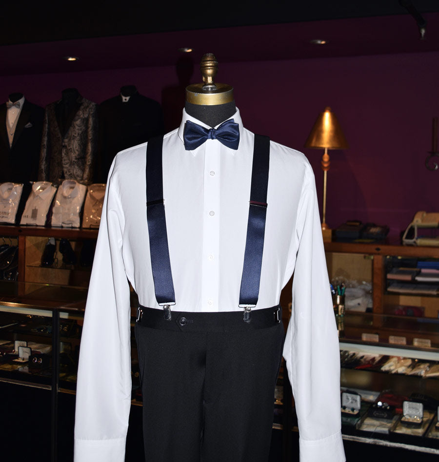 Mannequin wearing a white shirt with marine blue satin suspenders and a navy bow tie in a tuxclub tuxedo store.