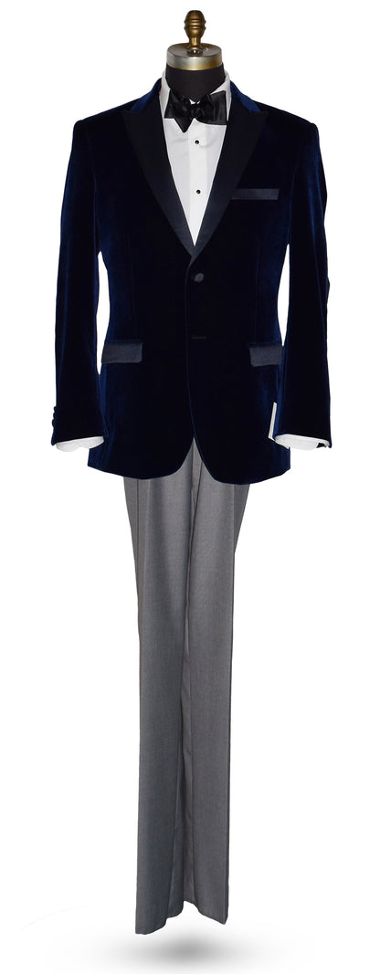 Navy velvet tuxedo with white tuxedo shirt and black satin bowtie with gray pants on a mannequin against a white background