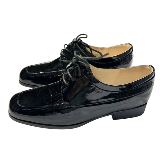 Side view Pair of black lace-up patent leather shoes on a white background