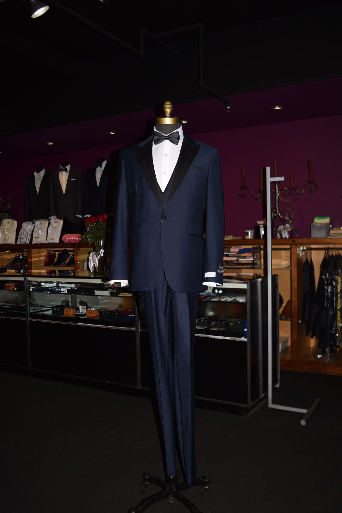 life-size mannequin Navy blue tuxedo with black lapels on a mannequin wearing a black bow tie inside of a fine mens store