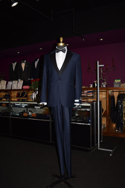 life-size mannequin Navy blue tuxedo with black lapels on a mannequin wearing a black bow tie inside of a fine mens store