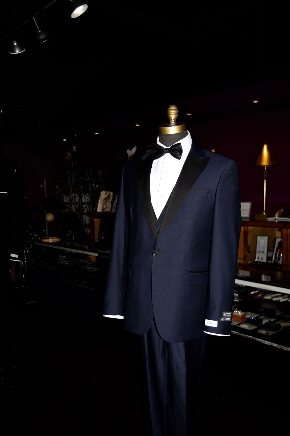 close-up mannequin Navy blue tuxedo with black lapels on a mannequin wearing a black bow tie inside of a fine mens store