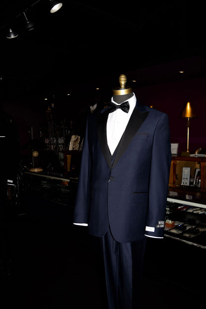close-up mannequin Navy blue tuxedo with black lapels on a mannequin wearing a black bow tie inside of a fine mens store