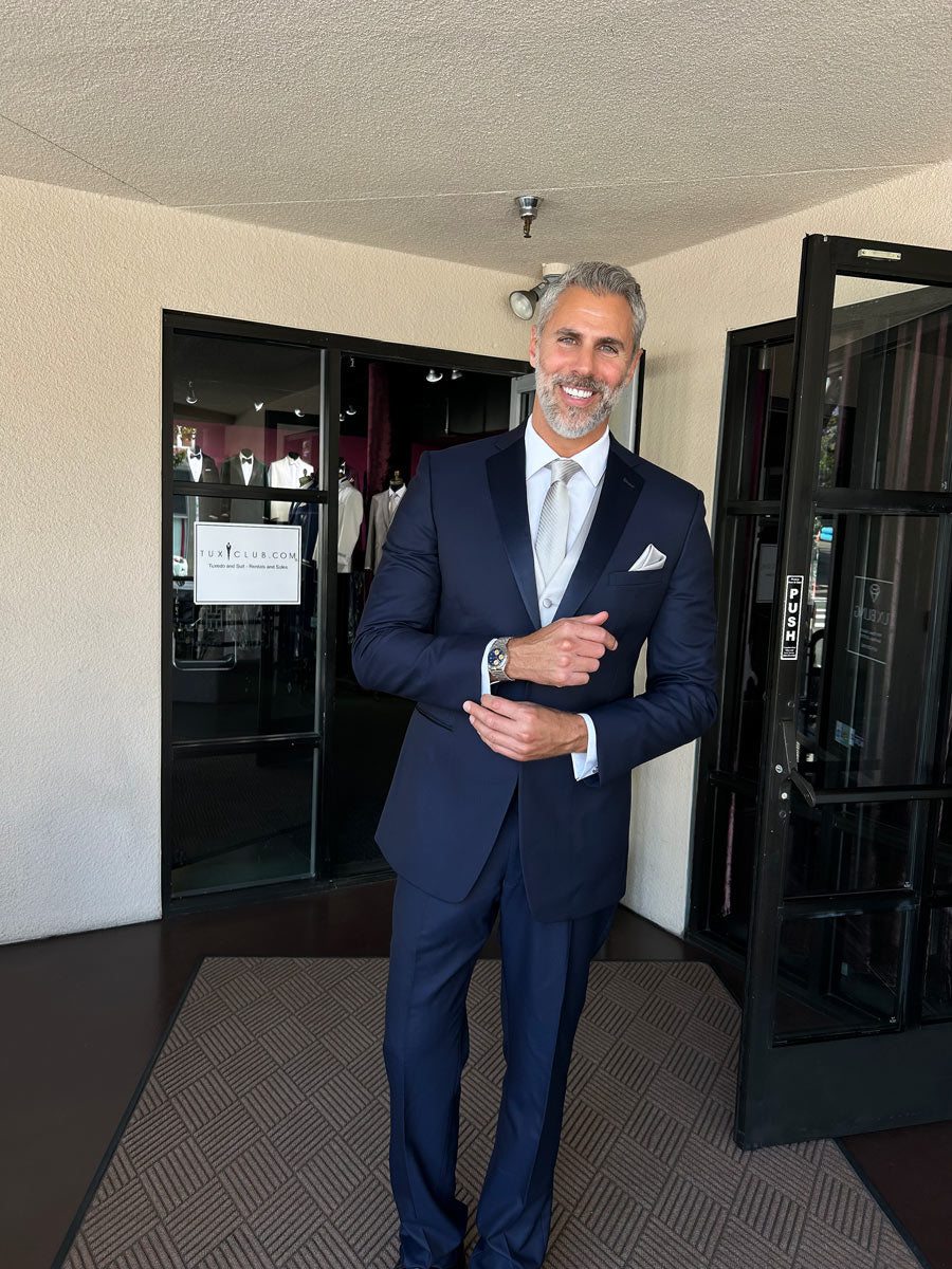 Handsome man wearing a navy blue tuxedo on the foyer of a tuxedo shop