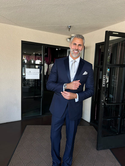 Handsome man wearing a navy blue tuxedo on the foyer of a tuxedo shop