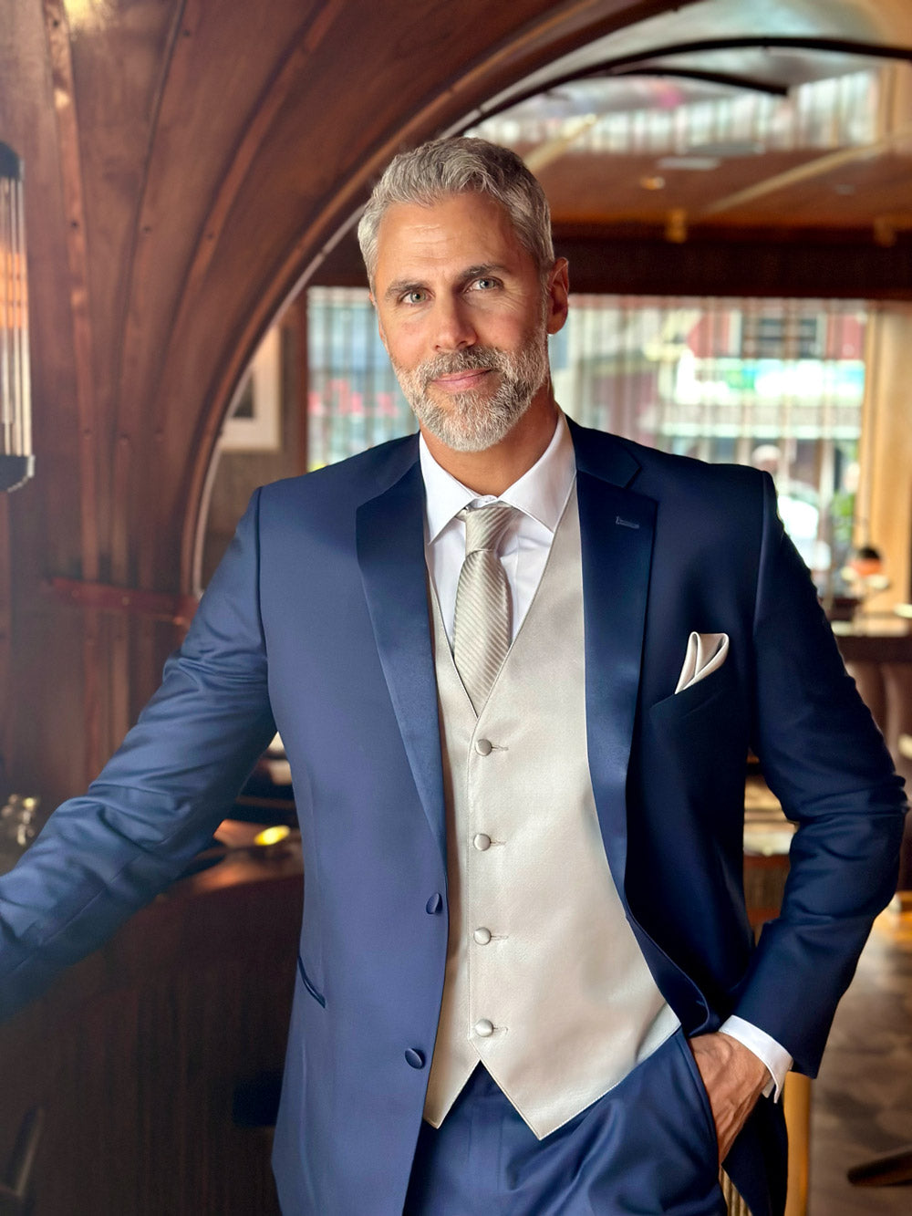 Front view of a model wearing a navy blue tuxedo with a gray vest and gray long necktie.
