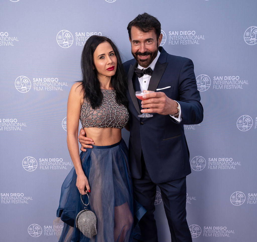 Man in a navy blue peak-lapel tuxedo and woman posing together at the San Diego International Film Festival