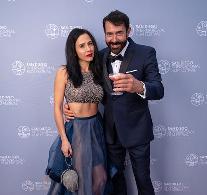 Man in a navy blue peak-lapel tuxedo and woman posing together at the San Diego International Film Festival