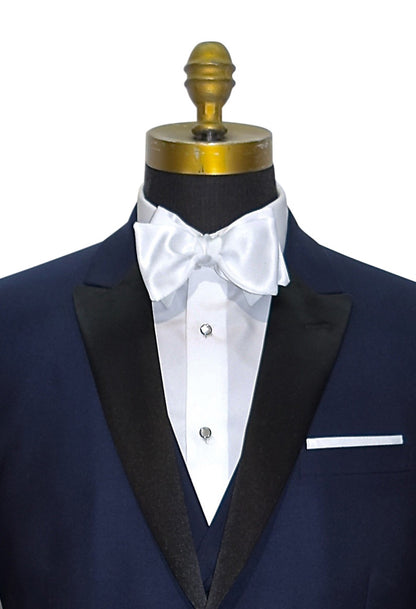 very close front view mannequin wearing a navy blue tuxedo with black peal lapels with matching navy tuxedo pants with white shirt and white satin bowtie against a white background