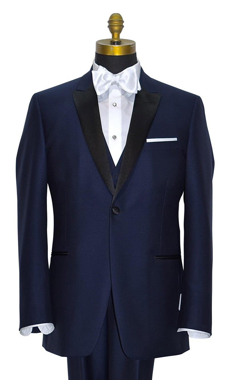 close-up front view mannequin wearing a navy blue tuxedo with black peal lapels with matching navy tuxedo pants with white shirt and white satin bowtie against a white background