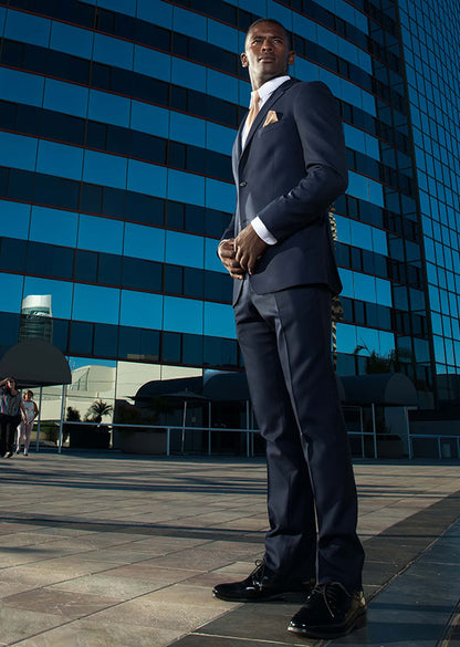 Man in a navy slim-fit suit and white shirt standing in front of the Marriott Marina in San Diego.