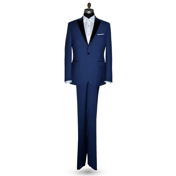 Mannequin wearing a royal-blue tuxedo with black peak lapel, royal blue trousers, and a white satin bowtie, against a white background.