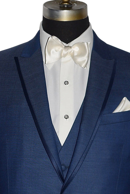very close up of a mannequin wearing a  new blue peak lapel tuxedo with ivory "tie-yourself" bowtie and ivory shirt with pearl studs and cufflinks against a white background