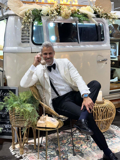 man wearing an ivory peak lapel dinner jacket white talking on the phone