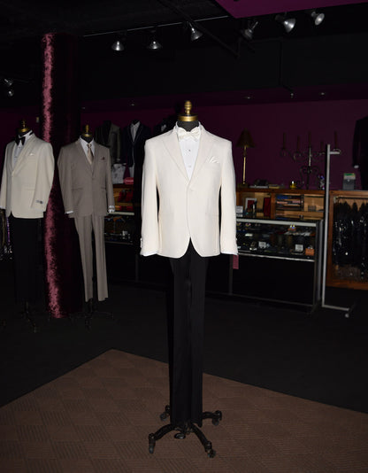 full length mannequin wearing an ivory peak lapel dinner jacket with white shirt and ivory satin bowtie in a fancy tuxedo shop with other tuxedos on mannequins