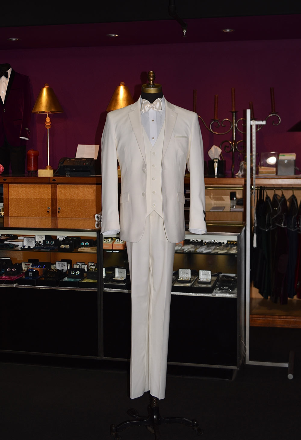 off-white mens suit with an off-white bowtie on a mannequin against a purple wall with clothing store display in the background