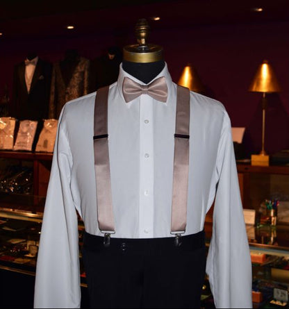 mannequin wearing a rose-gold "pre-tied" bowtie with rose-gold satin suspenders inside a tuxedo shop