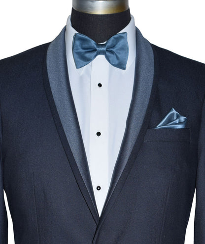 very close up life size mannequin wearing a serene blue shawl collar tuxedo with a blue bowtie against a white background
