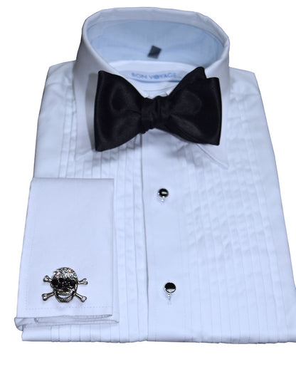 white tuxedo shirt wearing a black bowtie and "skull and crossbones" cufflinks against a white background