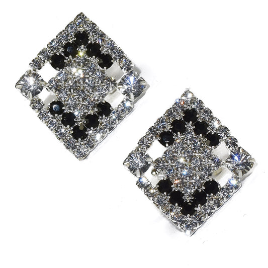 Pair of square-shaped cufflinks with black and clear gemstones on a white background