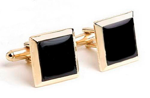 Gold cufflinks with black square onyx stone on a white background