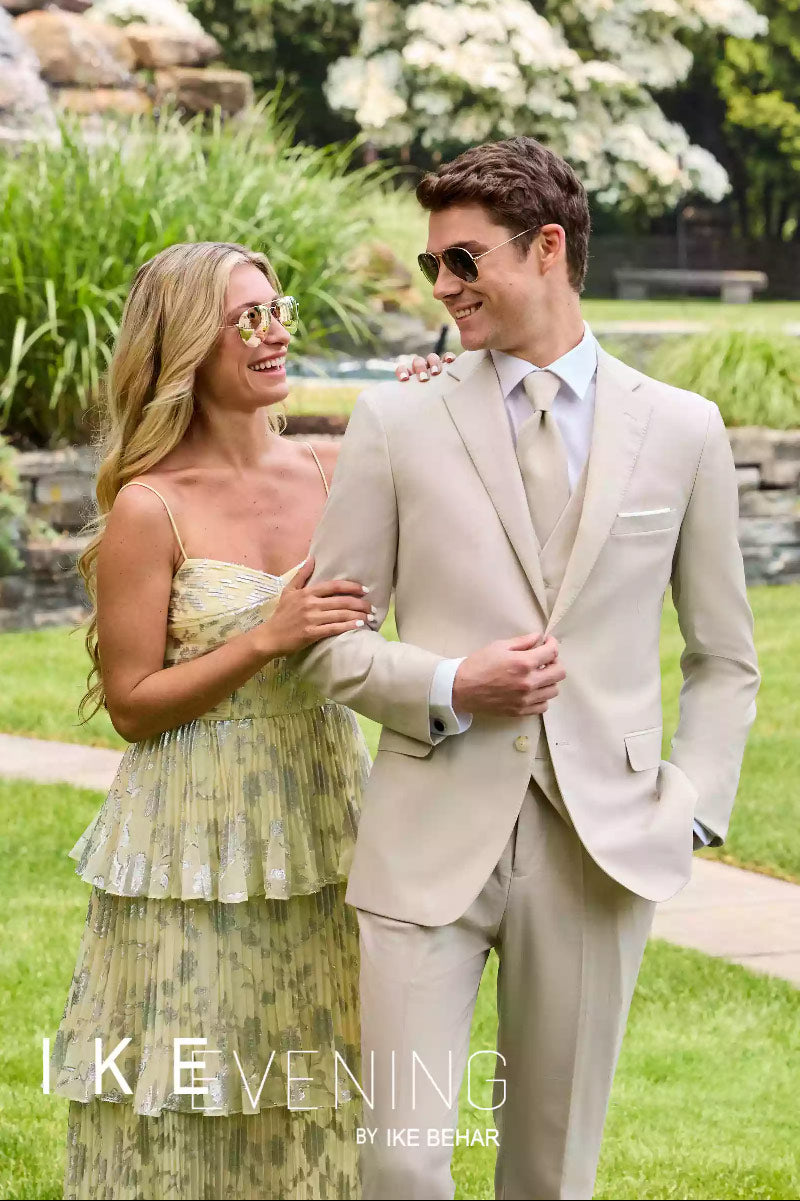 Front view of caucasian model wearing a slim fit suit with a female model while outdoors in a garden.