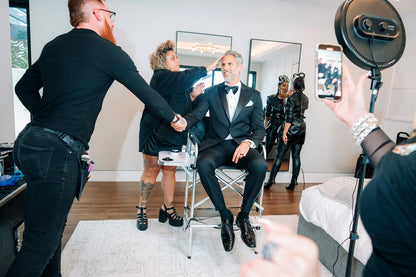 handsome man wearing a black peak lapel tuxedo while getting hair styled before the San Diego Film Festival. 