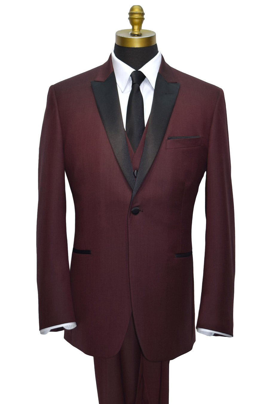 Maroon tuxedo with black lapels, a white shirt with long black dress tie and a maroon vest on a mannequin against a white background