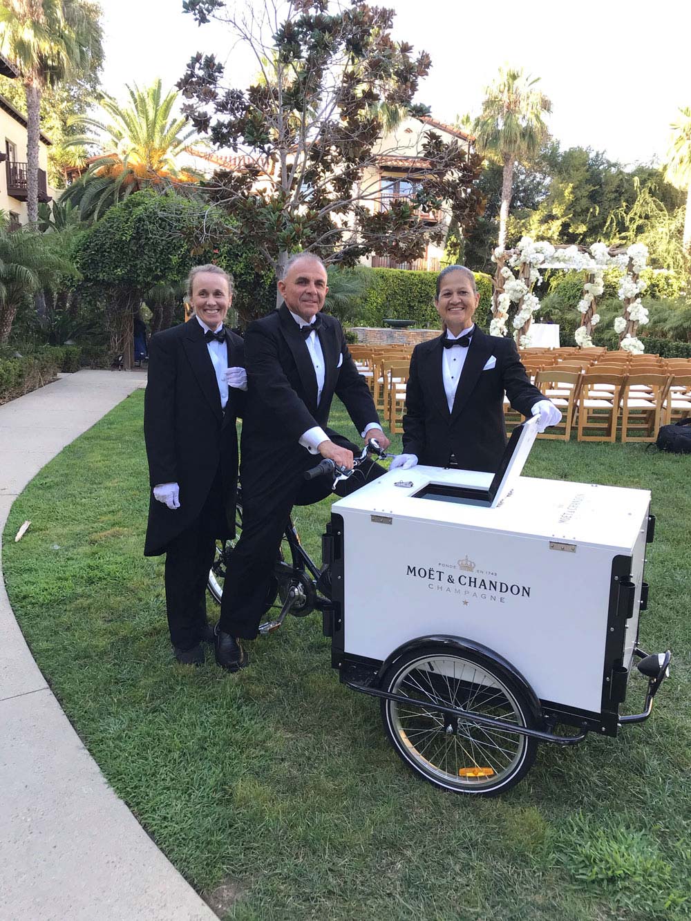 hotel staff wearing black cutaway morning suits at a wedding reception in a garden.