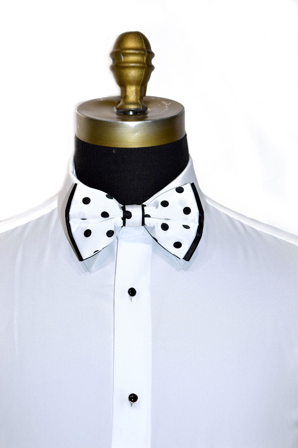 White shirt with a black and white polka dot bow tie on a mannequin against a white background