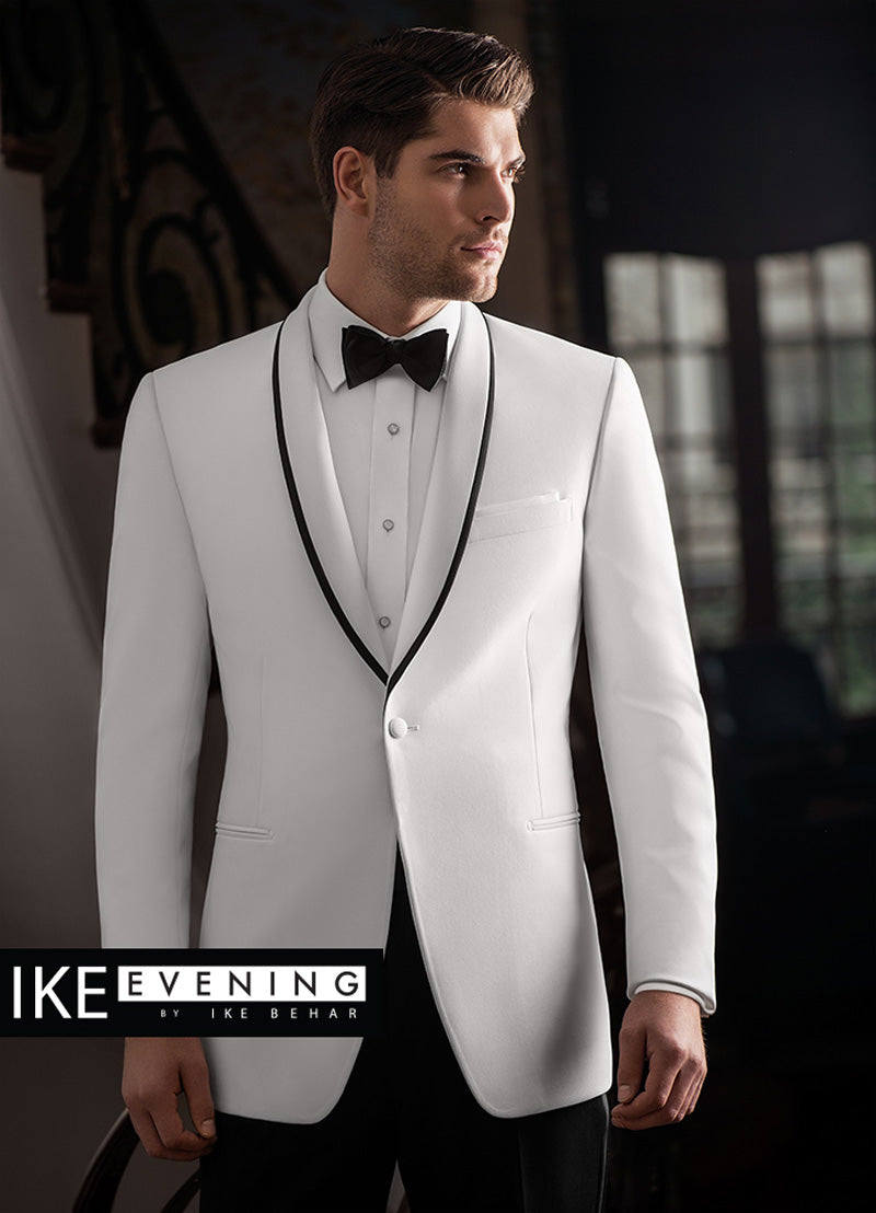 Man wearing a white shawl collar tuxedo with black trim on the lapel, standing against a dark background