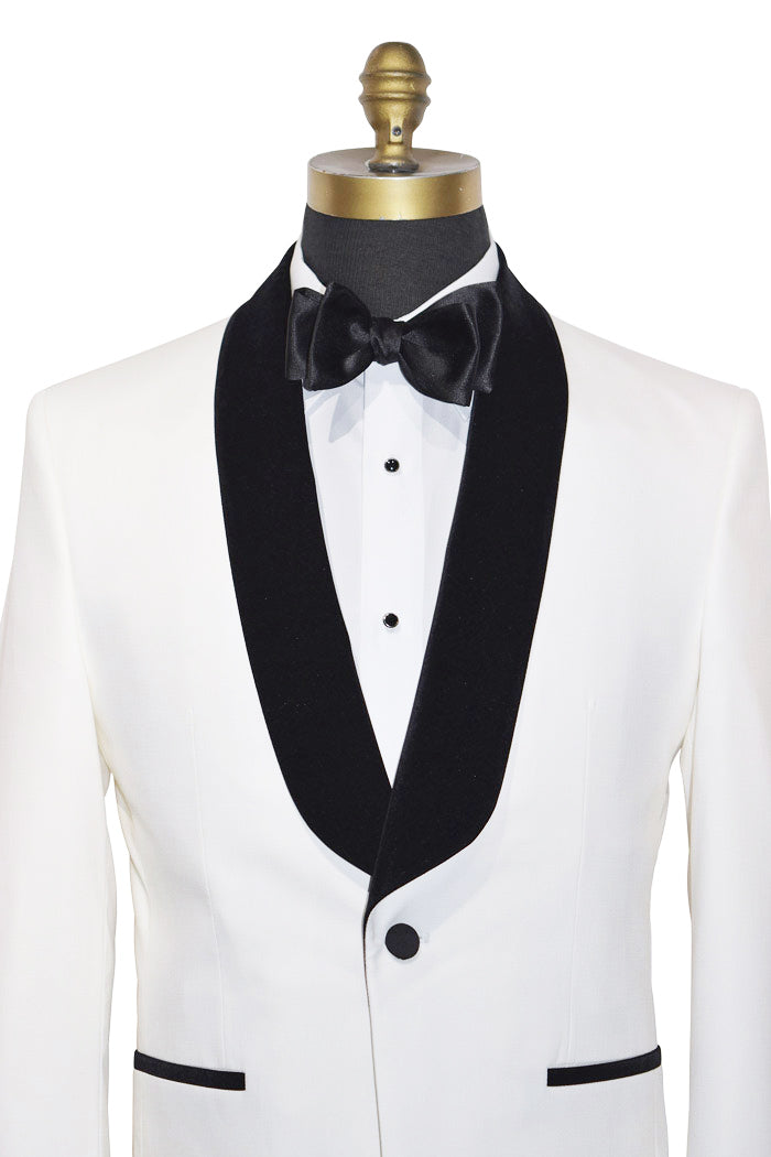 very close front of a tuxedo with black velvet shawl collar lapels and bow tie on a mannequin against a white background